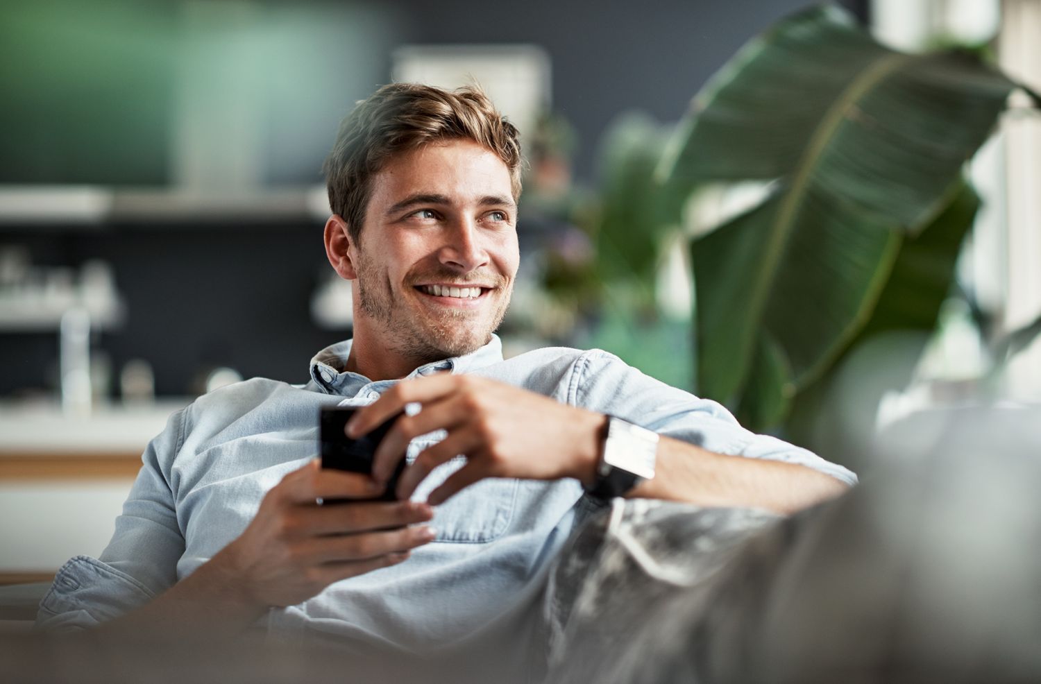 iv therapy patient model in a blue button up shirt smiling while holding his phone