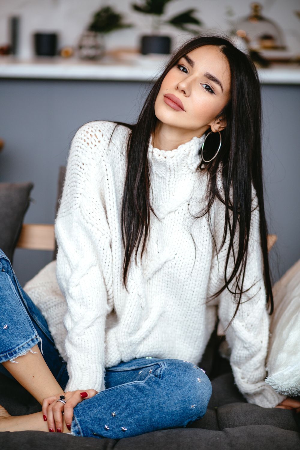 radiesse patient model in a white sweater and blue jeans sitting cross legged on the floor