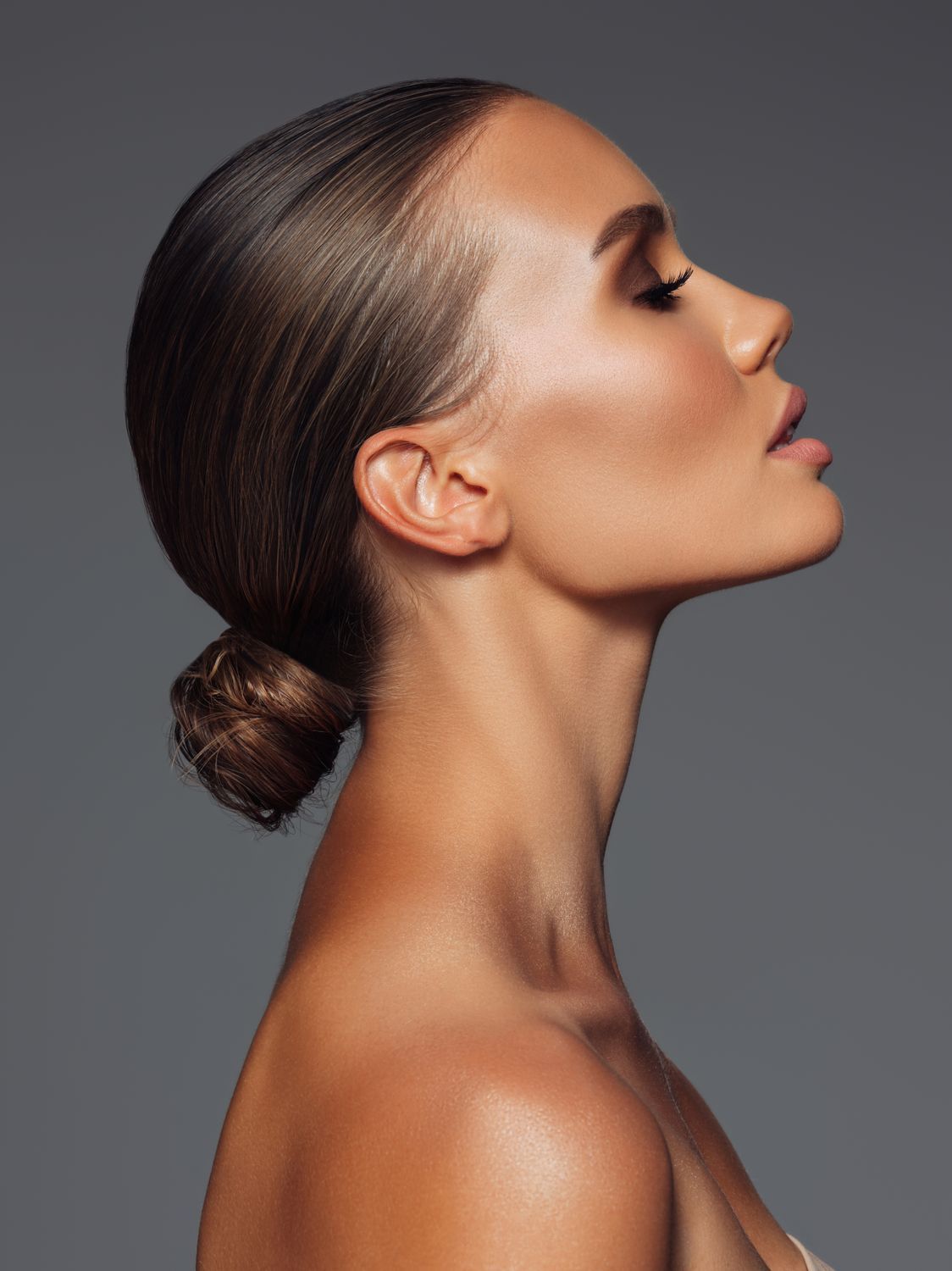 dermal filler patient model with her hair in a bun looking upwards with her lips slightly parted