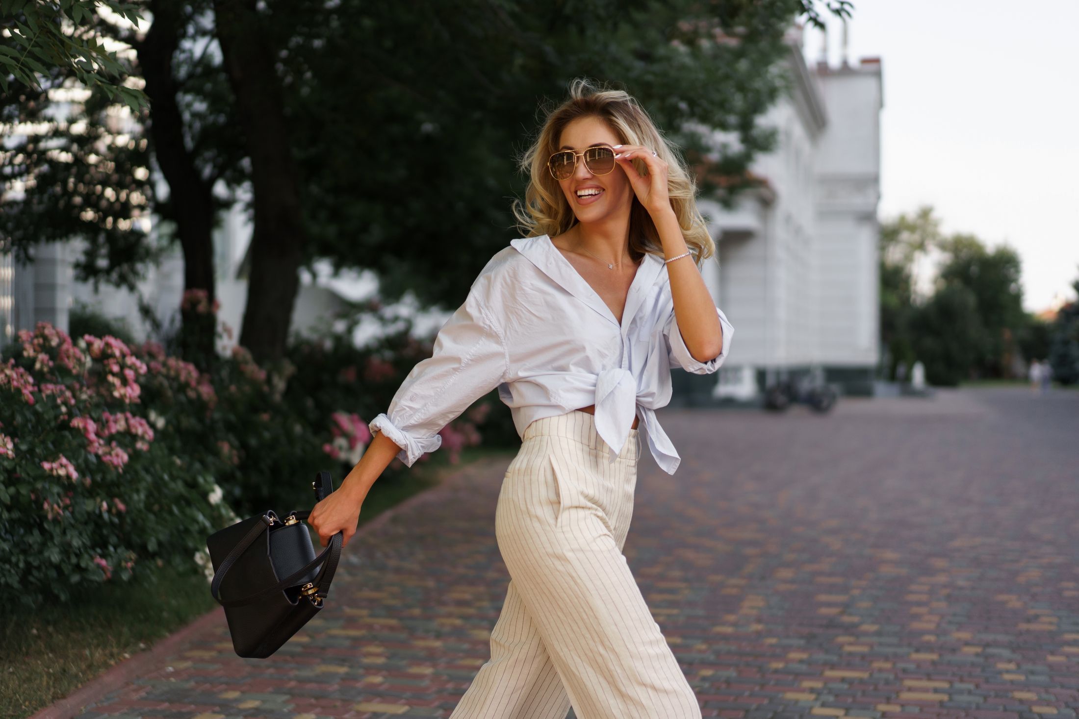 med spa patient model walking across the road wearing sunglasses and smiling