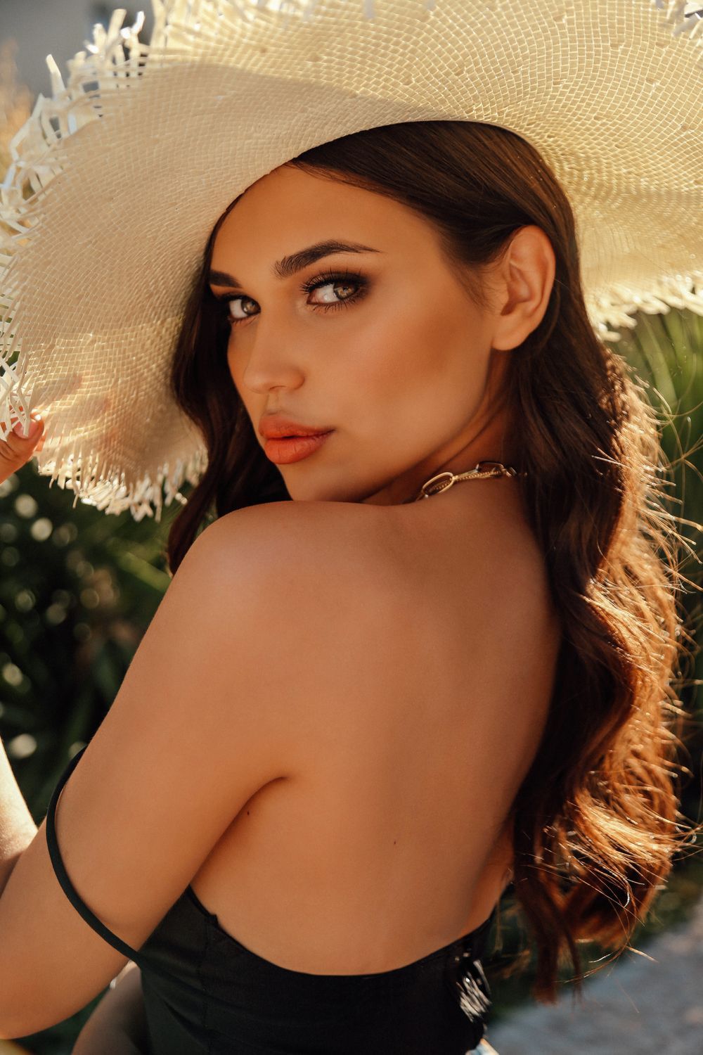 sculptra patient model in a straw sun hat and a black tanktop